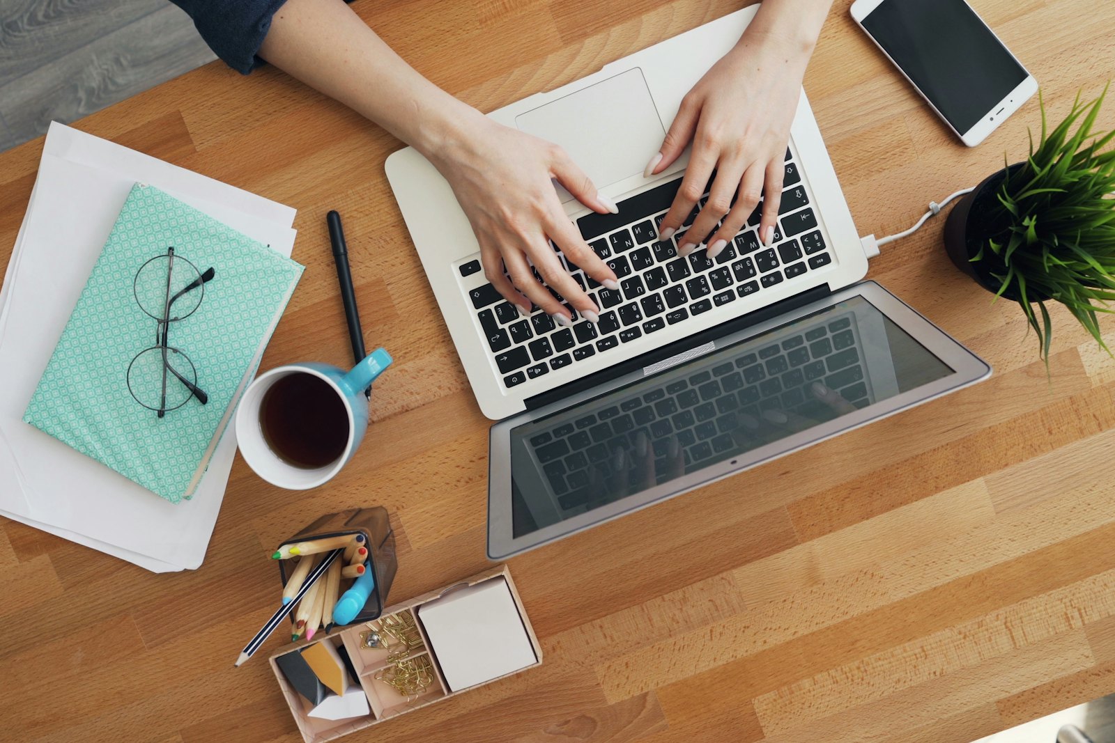 Person typing on a laptop at a wooden desk