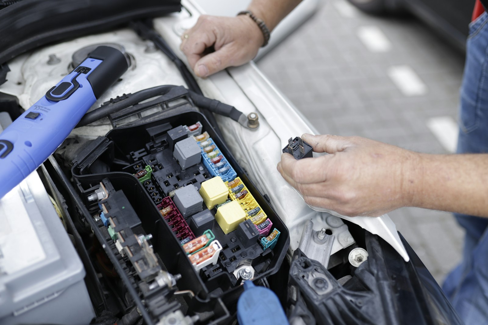 Technician checking the fuse box under the hood of a car