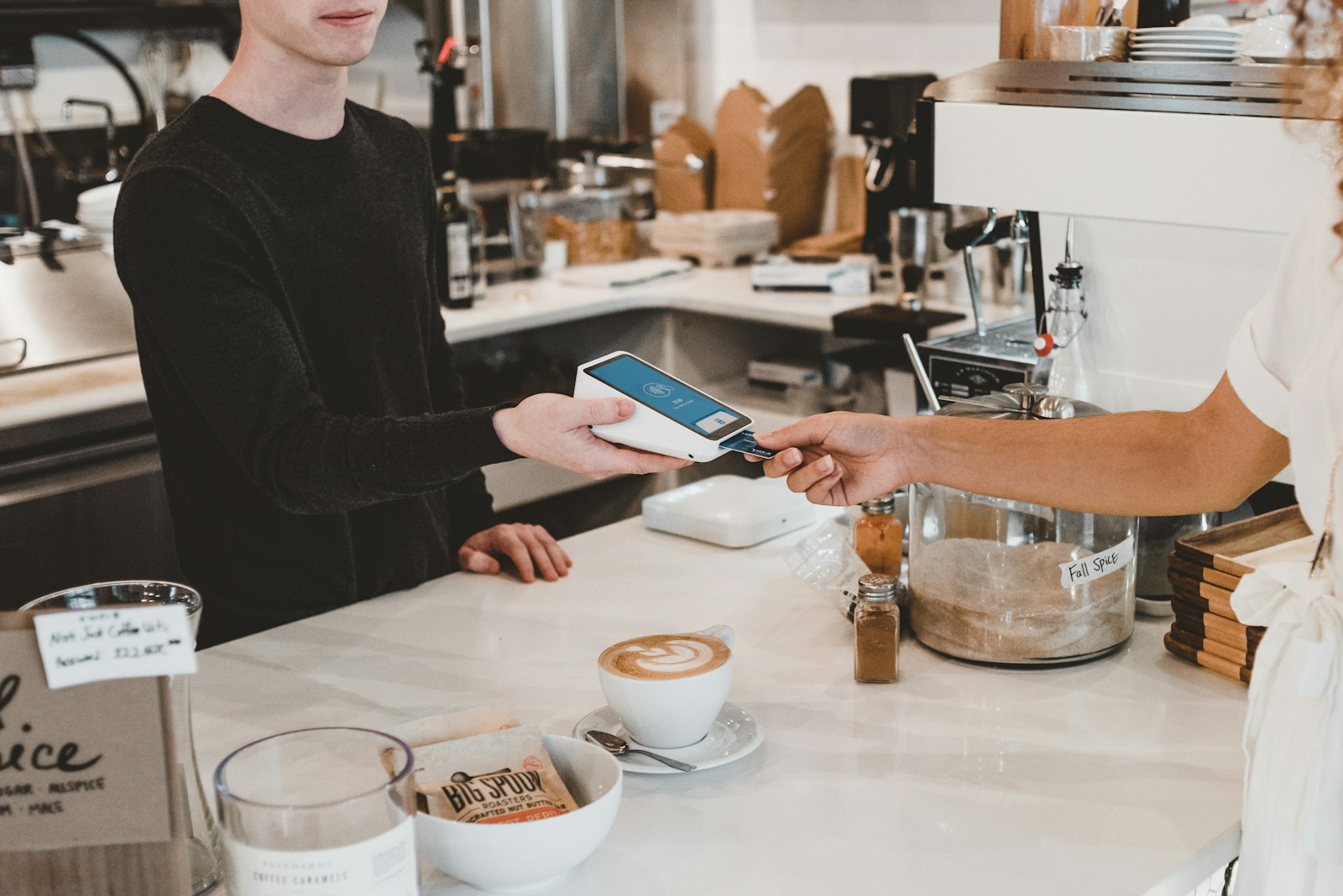 Customer paying by card on a handheld terminal at a café counter
