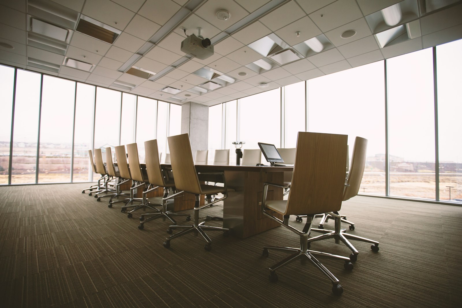 Boardroom table and chairs beside floor-to-ceiling windows